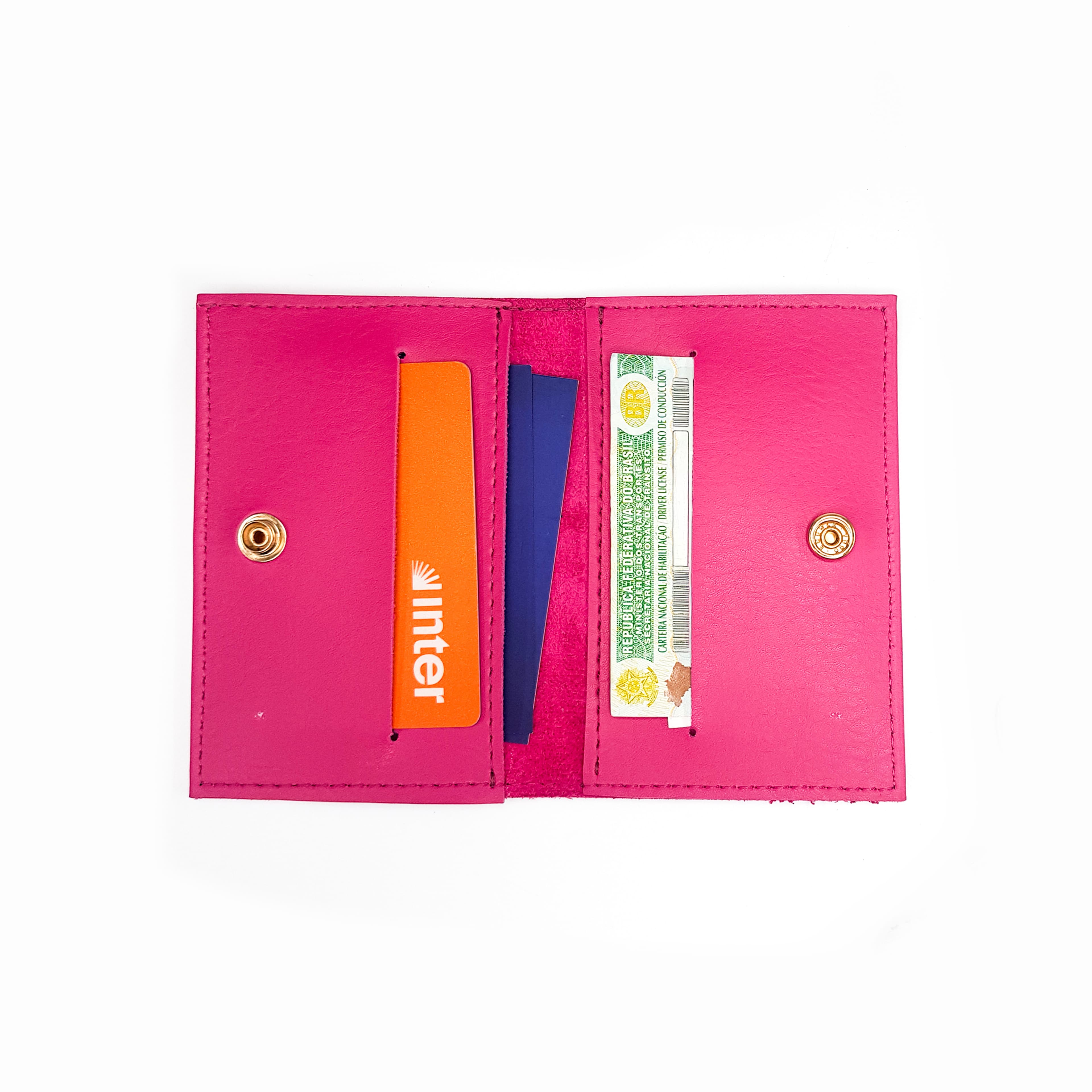 carteira rosa aberta com cartões e cédula em seu interior, vista de cima sobre fundo branco