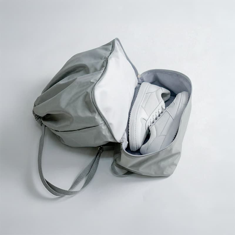 uma mochila sacola cinza aberta com com sapatos dentro