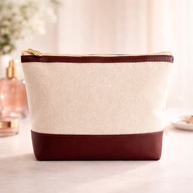 uma necessaire na cor bege e bordô sobre uma mesa em um ambienteiluminado com alguns itens ao fundo